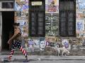 Una mujer con leggings con la bandera de Estados Unidos y un perro pasan junto a una casa
