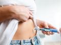 Image of an individual injecting insulin into their abdomen using a pen device. Demonstrates healthcare, diabetes management, and medication administration domestically, conveying a sense of responsibility and self-care.