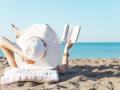 Una mujer disfruta leyendo un libro en la playa (que, seguramente, no sea el de Morlans)
