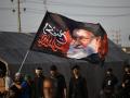 Peregrinos musulmanes chiítas portan una bandera con el retrato del asesinado líder supremo de Irán, el ayatolá Ali Khamenei, mientras marchan hacia la ciudad santa de Karbala,