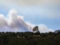 El humo de un fuego cercano sobrevuela una antena de la NASA