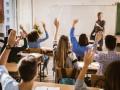 Estudiantes levantando las manos de una clase