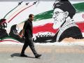 Un hombre pasa frente a un mural que representa al difunto líder supremo iraní, el ayatolá Ali Jamenei, en Teherán