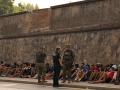 Soldados españoles conversan mientras observan a inmigrantes sentados en el suelo, antes de escoltarlos de regreso a Marruecos