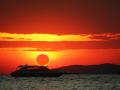 Fenómeno increíble de eclipse de sol parcial sobre barco de silueta en el mar y el cielo de la puesta de so