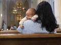 Una madre junto a su bebé, esperando que empiece la Eucaristía
