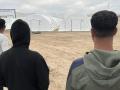 Tres inmigrantes junto al nuevo campamento, en el puerto de Ceuta