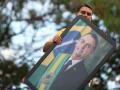 Brazilian right-wing presidential candidate Flavio Bolsonaro holds a picture of his father, convicted former President Jair Bolsonaro, during a motorcade with supporters in Goiania, Brazil, on September 27, 2026. Brazil will hold presidential election on October 4, 2026. (Photo by Sergio Lima / AFP)