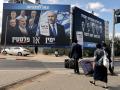 Los peatones cruzan una calle frente a una pancarta (izquierda) con la imagen del primer ministro israelí Benjamin Netanyahu, del partido Likud, y miembros de la oposición, antes de las elecciones legislativas del país en Bnei Brak