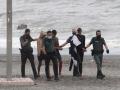 Miembros de la Guardia Civil detienen a varios de los inmigrantes que han intentado llegar a nado hoy Miércoles a la playa del Tarajal, en Ceuta. EFE / Reduan.