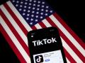 Fotografía de archivo que muestra la aplicación TikTok en la pantalla de un teléfono con la bandera estadounidense de fondo