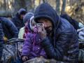 A man holding a child reacts as the members of the Kurdish family from Dohuk in Iraq wait for the border guard patrol, near Narewka, Poland, near the Polish-Belarus border on November 9, 2021. - The three-generation family of 16 members with seven minors, including the youngest who is five months old, spent about 20 days in the forest and was pushed back to Belarus eight times. They claim they were beaten and frightened with dogs by Belarusian soldiers. (Photo by Wojtek RADWANSKI / AFP)