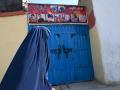 Una mujer ataviada con un burka pasa frente a la casa de Aimal Ahmadi, cuya hija Mailka y su hermano mayor Zimarai Ahmadi estaban entre los 10 familiares asesinados por un ataque con aviones no tripulados estadounidenses mal dirigido el 29 de agosto en Kabul, la fotografía fue tomada el 14 de diciembre de 2021