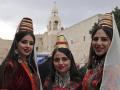 Un grupo de mujeres palestinas, vestidas con ropajes tradicionales, posan en una fotografía en el exterior de la Iglesia de la Natividad en Belén, ubicada donde tradicionalmente se cree que nació Jesús