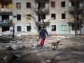 Un hombre camina con su perro frente a un edificio de apartamentos de Mariúpol destrozado por las bombas