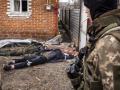Un soldado ucraniano observa en cadáver de uno de sus invasores