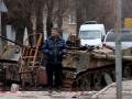Un hombre camina frente a un tanque destrozado en Bucha, Ucrania