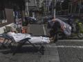 Un repartidor con equipo de protección duerme la siesta en la calle en medio del confinamiento
