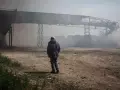 Un hombre observa como se eleva el humo de unos silos calcinados