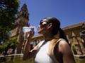 Una joven bebe agua para refrescarse en el Patio de los Naranjos de Córdoba