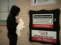 Una mujer con su bebé, frente a una caja refugio de Safe Haven