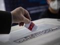 Un miembro del Servel (Servicio Electoral) muestra cómo emitir su voto en un simulacro electoral