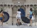 Varias chicas con sus paraguas frente a las torres de Serrano de Valencia