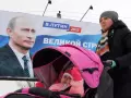 Pancarta de Vladimir Putin de las elecciones de 2012 mientras una madre pasea con su hijo