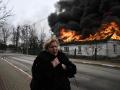 Una mujer frente a una casa en llamas después de ser bombardeada en la ciudad de Irpin