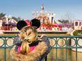 Una niña con orejas de Minnie Mouse ve a lo lejos unas atracciones de Fantasyland, en Disneyland París