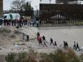 Inmigrantes caminan a lo largo del lado estadounidense del río Bravo debajo del muro fronterizo para entregarse a los agentes de la Patrulla Fronteriza de EE.UU. en El Paso, Texas