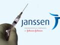 Una mano sujeta una vacuna con el logo de la compañía farmacéutica Janssen en el fondo