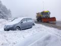 Un coche cubierto de nieve y una máquina quitanieves en Navacerrada