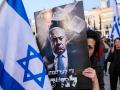 Una manifestante se cubre la cara con un cartel contra el primer ministro israelí Benjamin Netanyahu