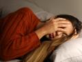 Una mujer con dolor de cabeza reposa en su cama