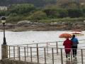 Dos personas caminan con paraguas este martes, en la localidad de San Cibrao en Lugo