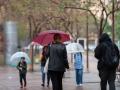 Varias personas con paraguas pasean por una calle de Barcelona