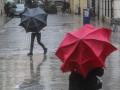 Dos personas sostienen sus paraguas para refugiarse de la lluvia