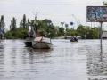 Residentes y trabajadores de los servicios de rescate usan barcas para moverse en una zona inundada de Jersón, Ucrania