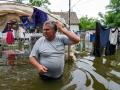 Un residente local camina por el patio inundado de su casa en Mykolayiv