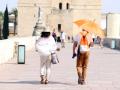 Dos turistas caminan por el Puente Romano de Córdoba en una jornada de calor.