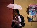 Una pareja de turistas pasea por la judería de Córdoba protegidos por un paraguas