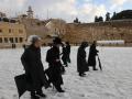 Varias personas caminan sobre la nieve en Jerusalén cubierta de nieve en enero de 2022