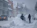 Dos personas quitan la nieve de un coche en la calle en Kristiansand, Noruega