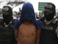 Oficiales de la Policía Nacional de Ecuador escoltan a un hombre detenido bajo sospecha de pertenecer a una banda criminal