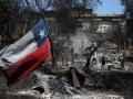 Una bandera chilena ondea mientras los vecinos limpian sus tierras y queman casas en Villa Independencia, región de Valparaíso
