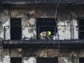 Bomberos y Policía Científica inspeccionan un cuerpo en un balcón del edificio incendiado en el barrio de Campanar de Valencia