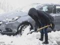 Una mujer trata de despejar la nieve acumulada en la carretera para poder circular con su vehículo este sábado en O Cebreiro, Lugo