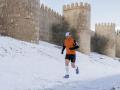 Un hombre corre en una calle cubierta de nieve frente a las murallas de Ávila