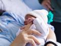 Un bebé recién nacido agarra la mano de su madre